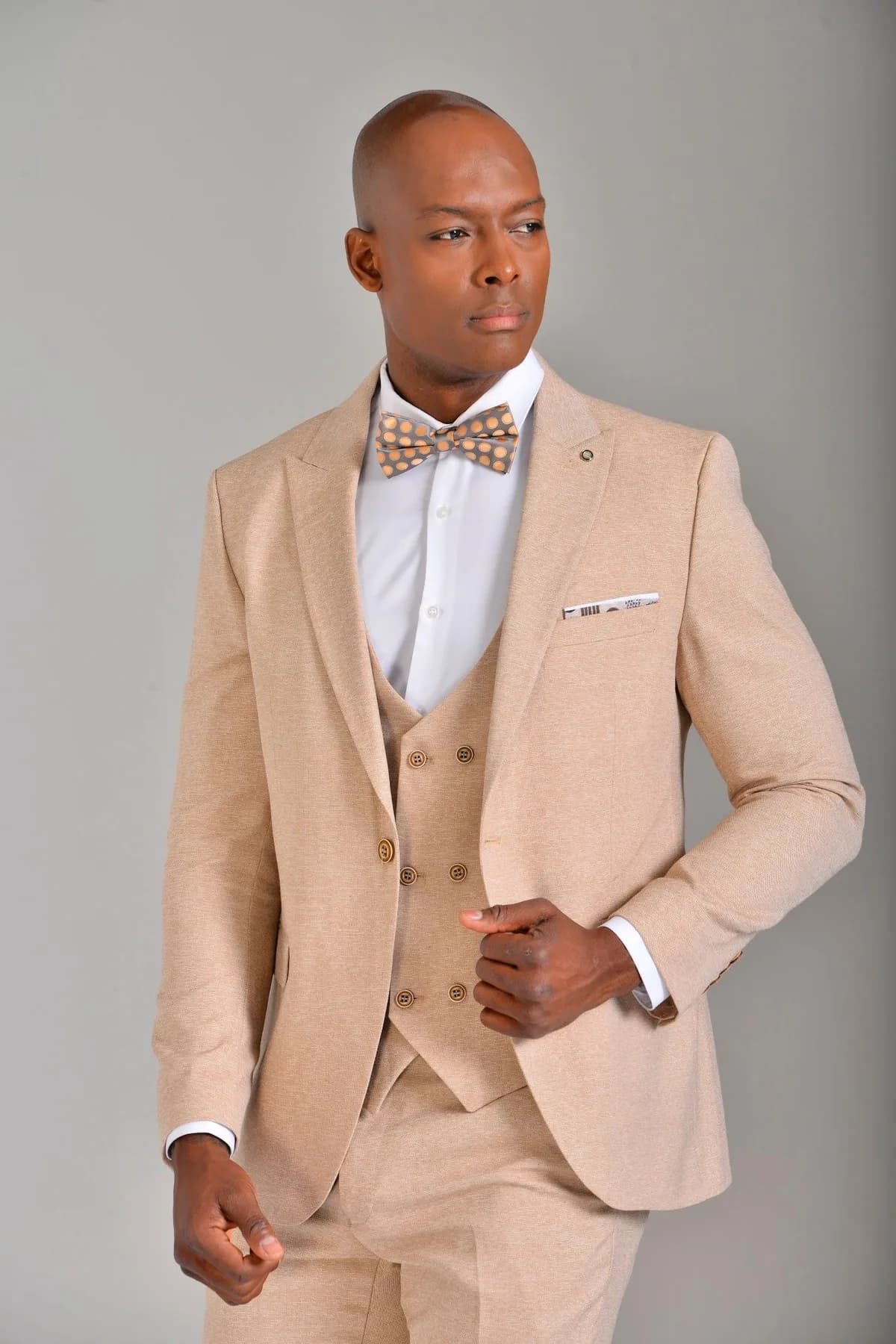 Traje de novio beige de tres piezas para una boda al aire libre.
