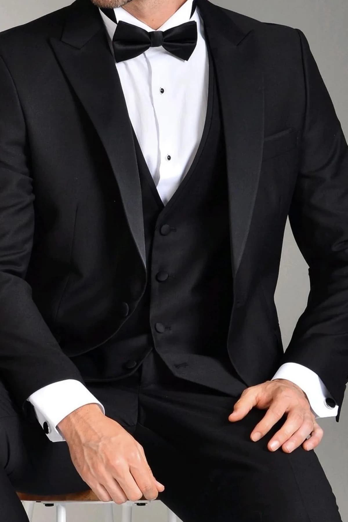 Esmoquin negro de tres piezas con corbatín y camisa blanca, para una boda de noche.